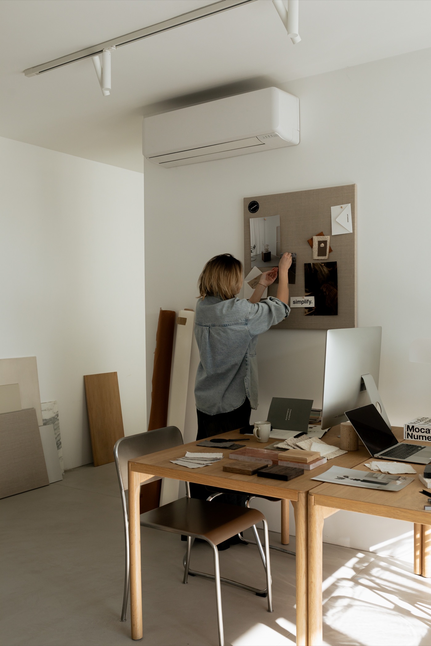 Céline Marchand pinning images to a linen mood board in the sunlit Maison Ardoise studio