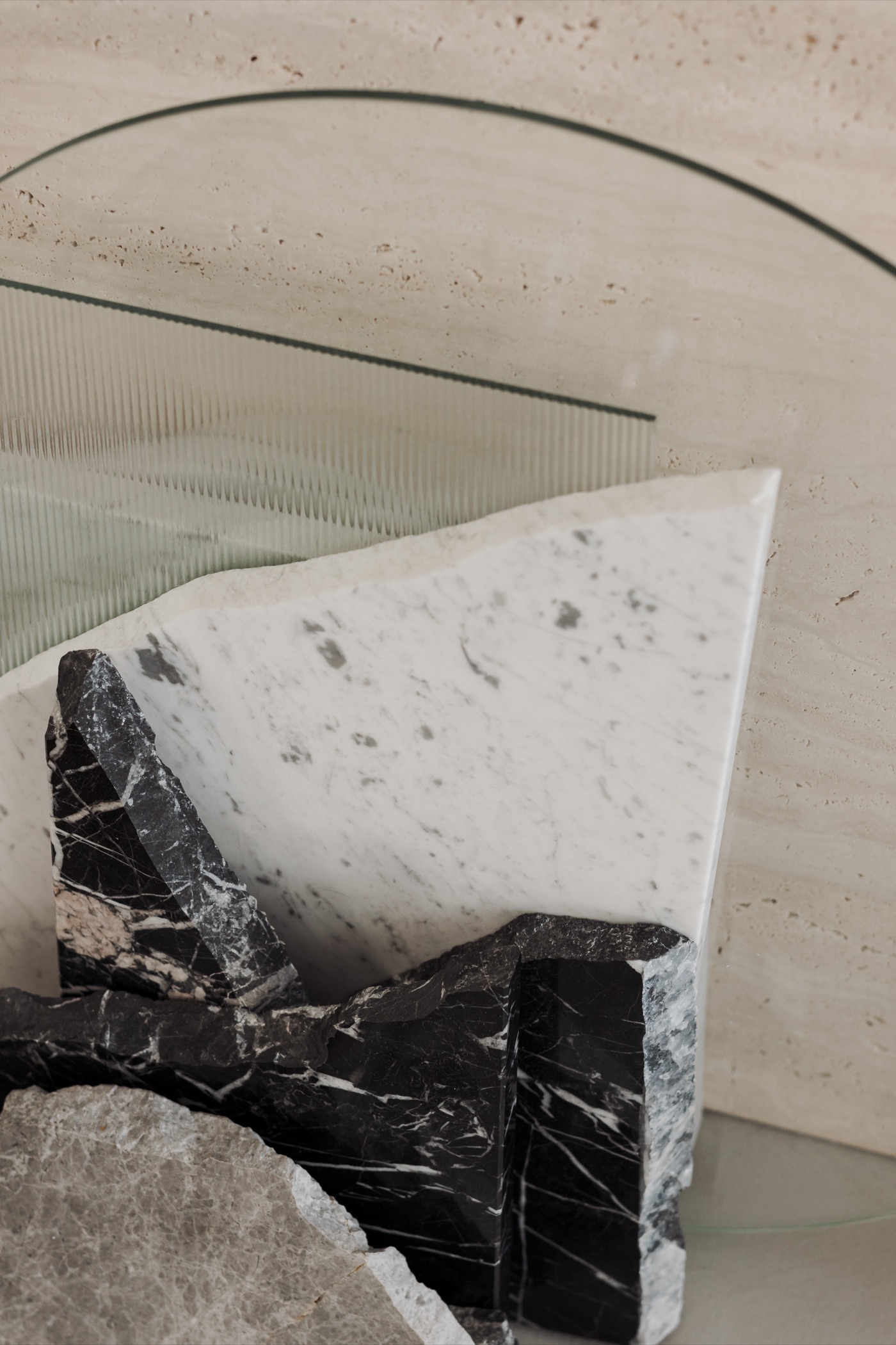 Fragments of white Carrara and black Nero Marquina marble with reeded glass against travertine
