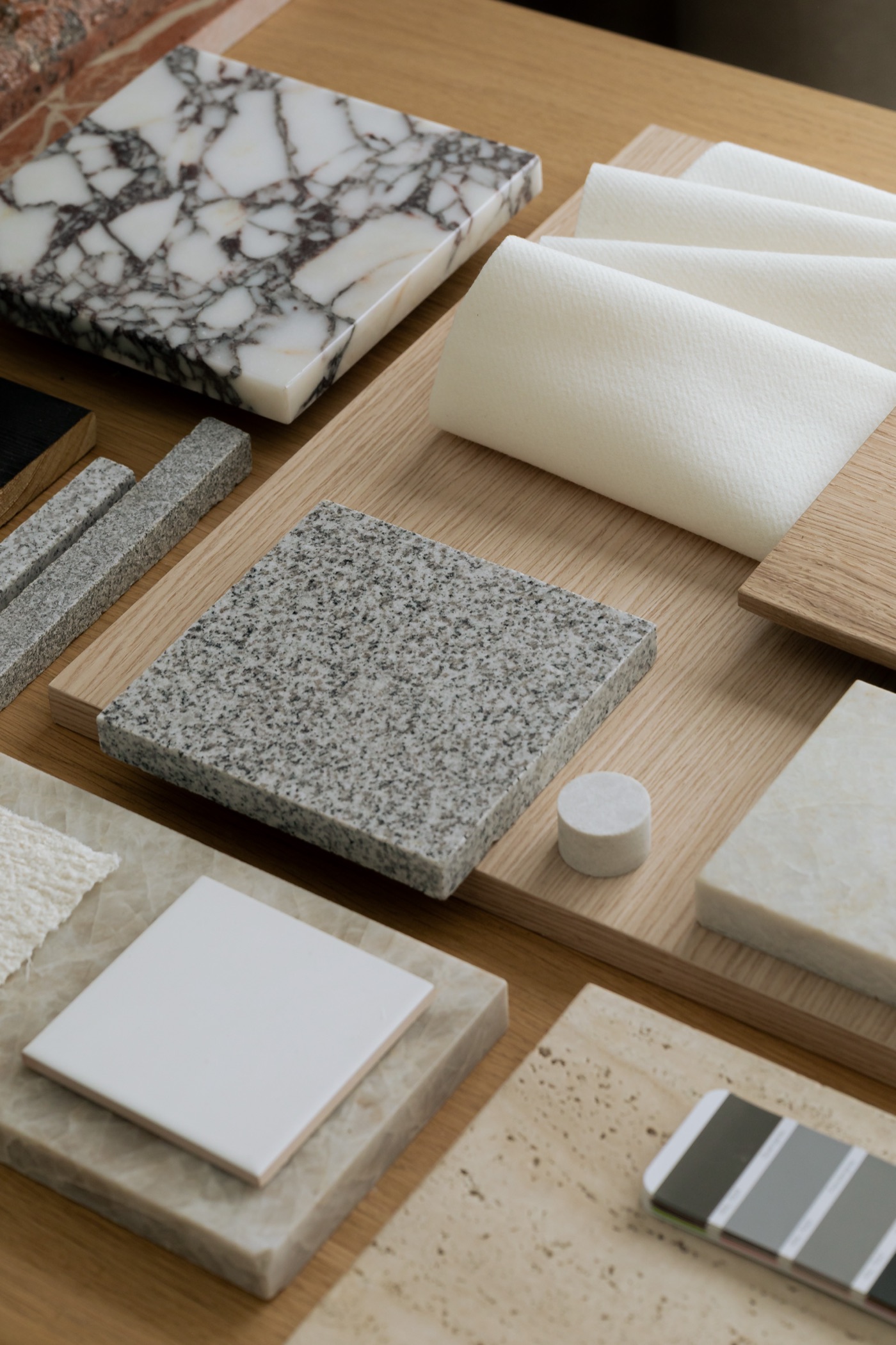 Material samples of marble, granite, travertine, oak and textured fabric on an oak table