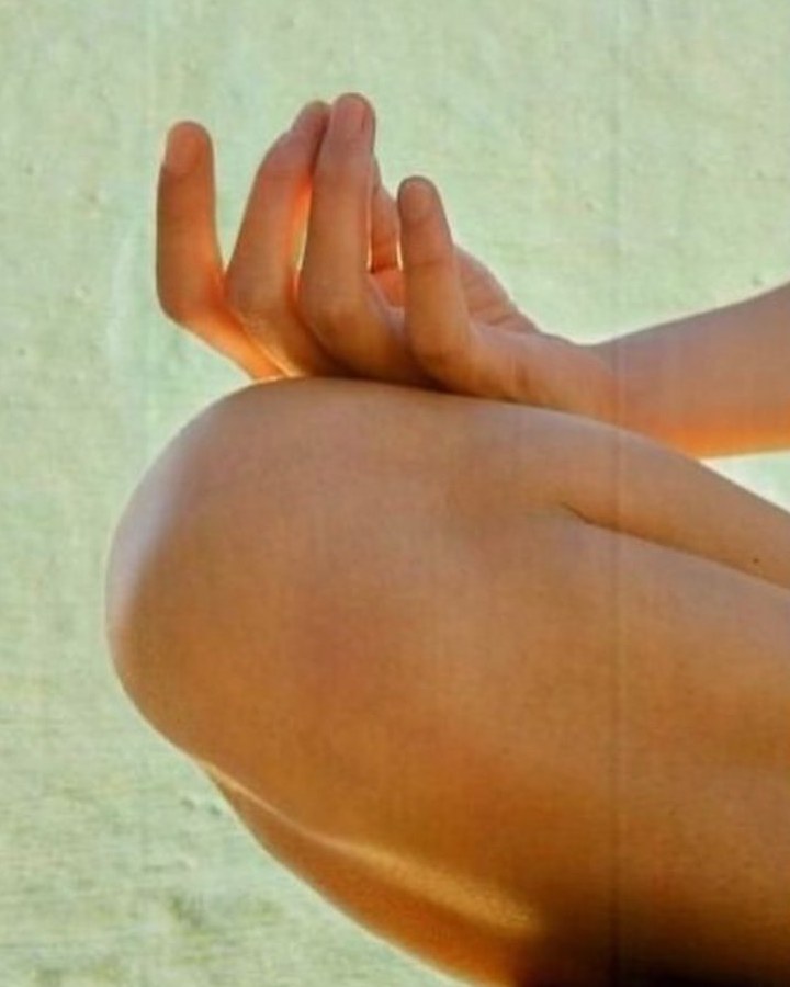 A hand resting on the knee in a mudra during seated meditation