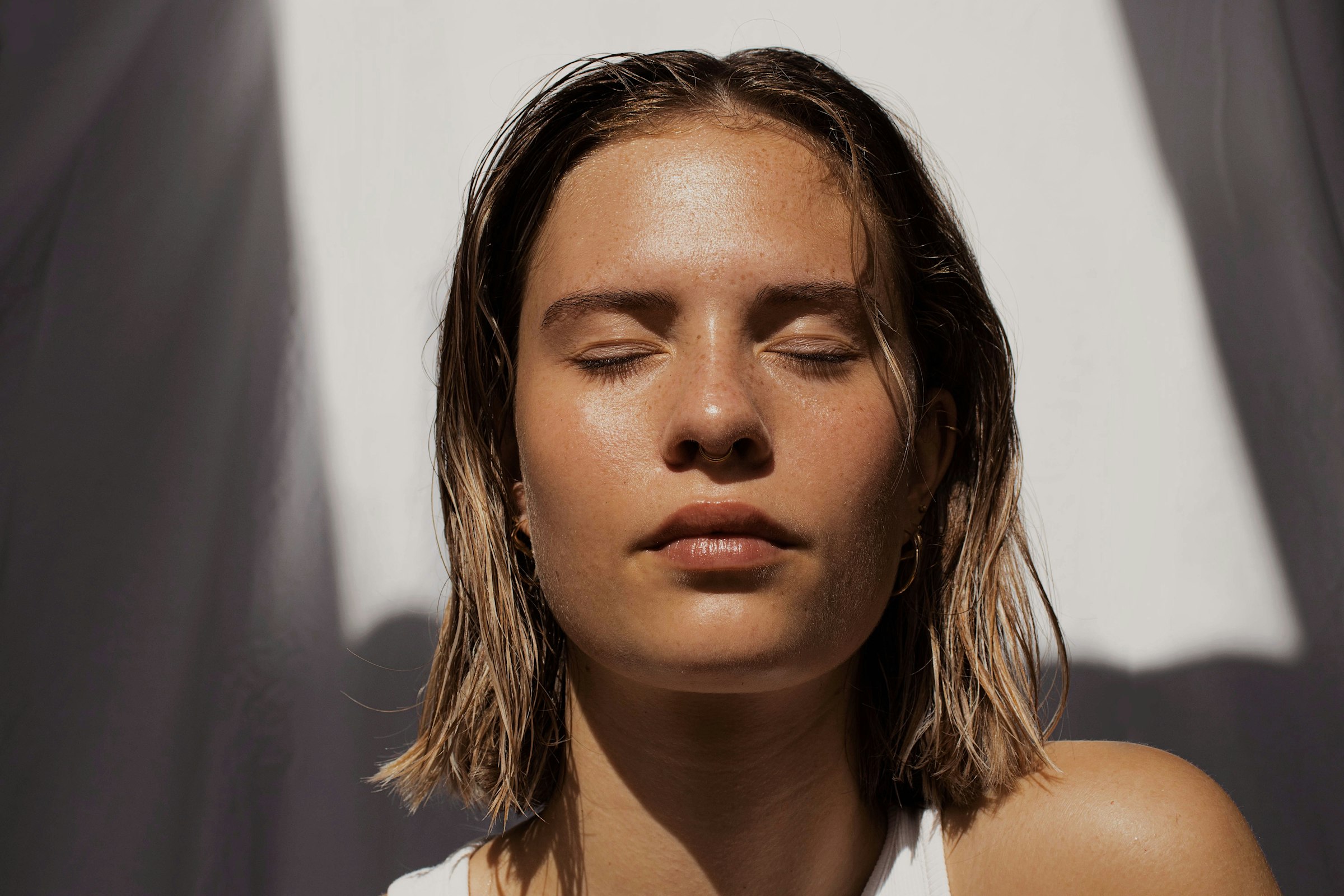 Close portrait of a woman with closed eyes and clear, dewy skin