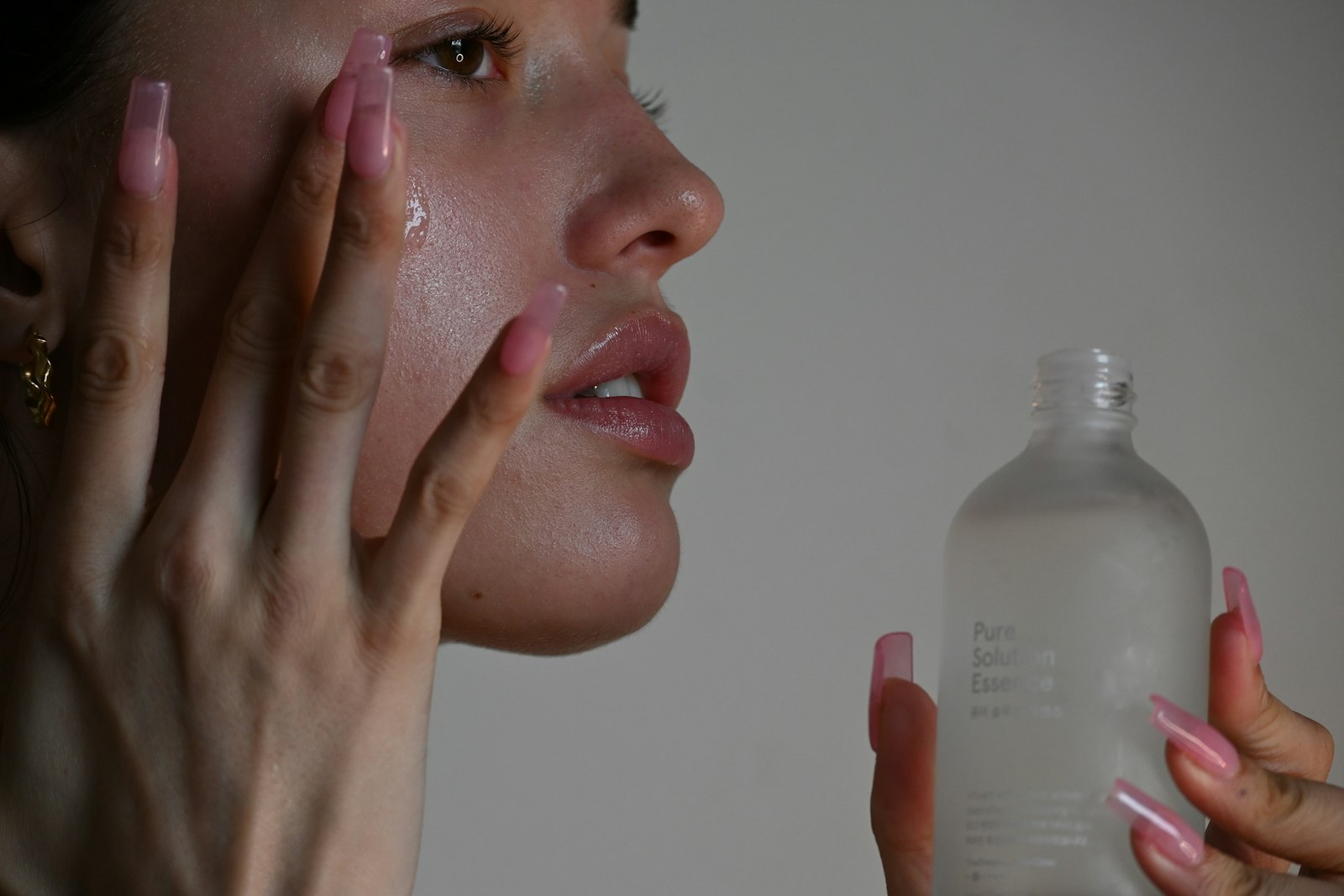 Woman pressing serum into her cheek, skin glowing