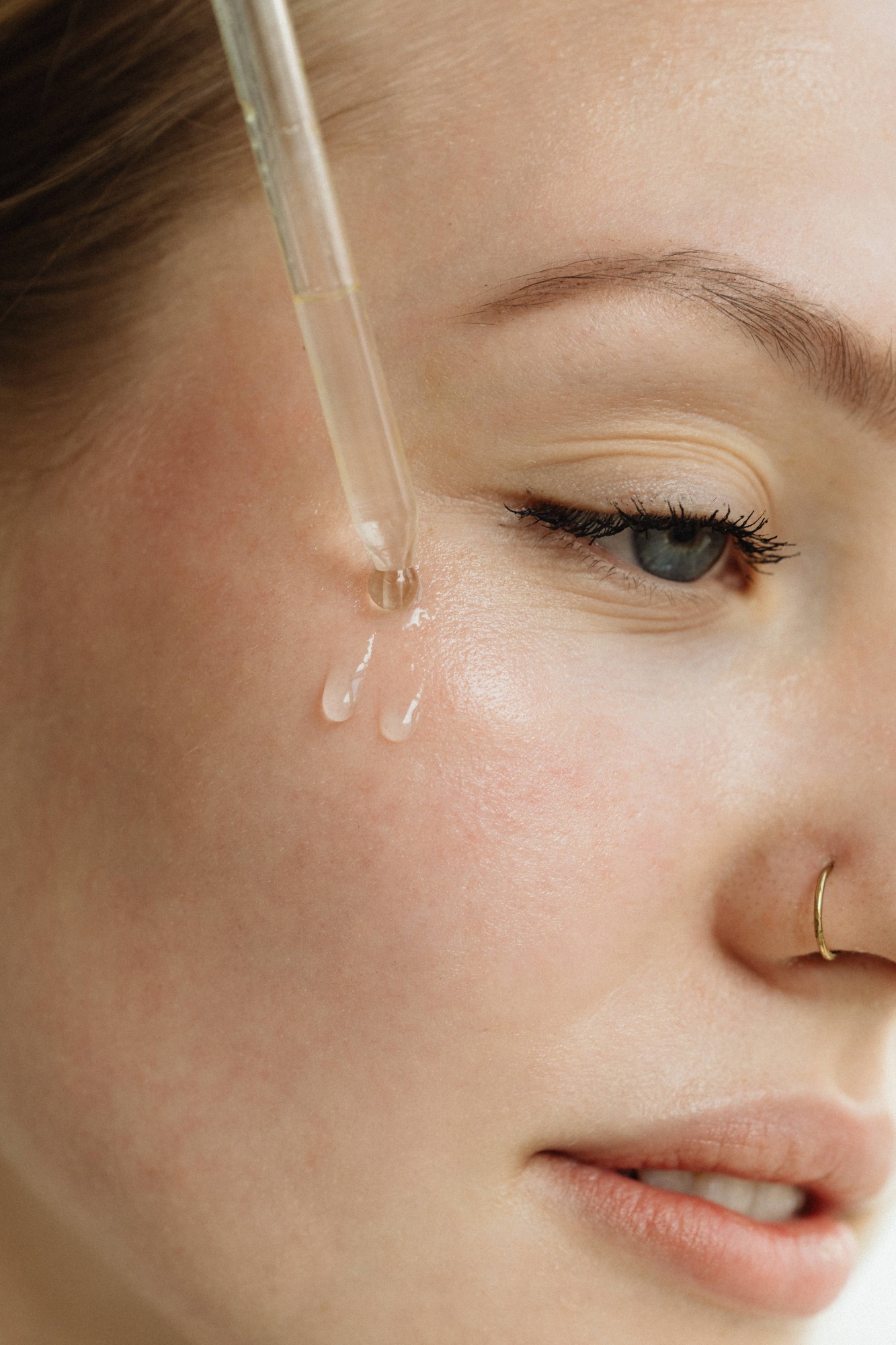 Clear serum applied with a glass dropper to the cheek