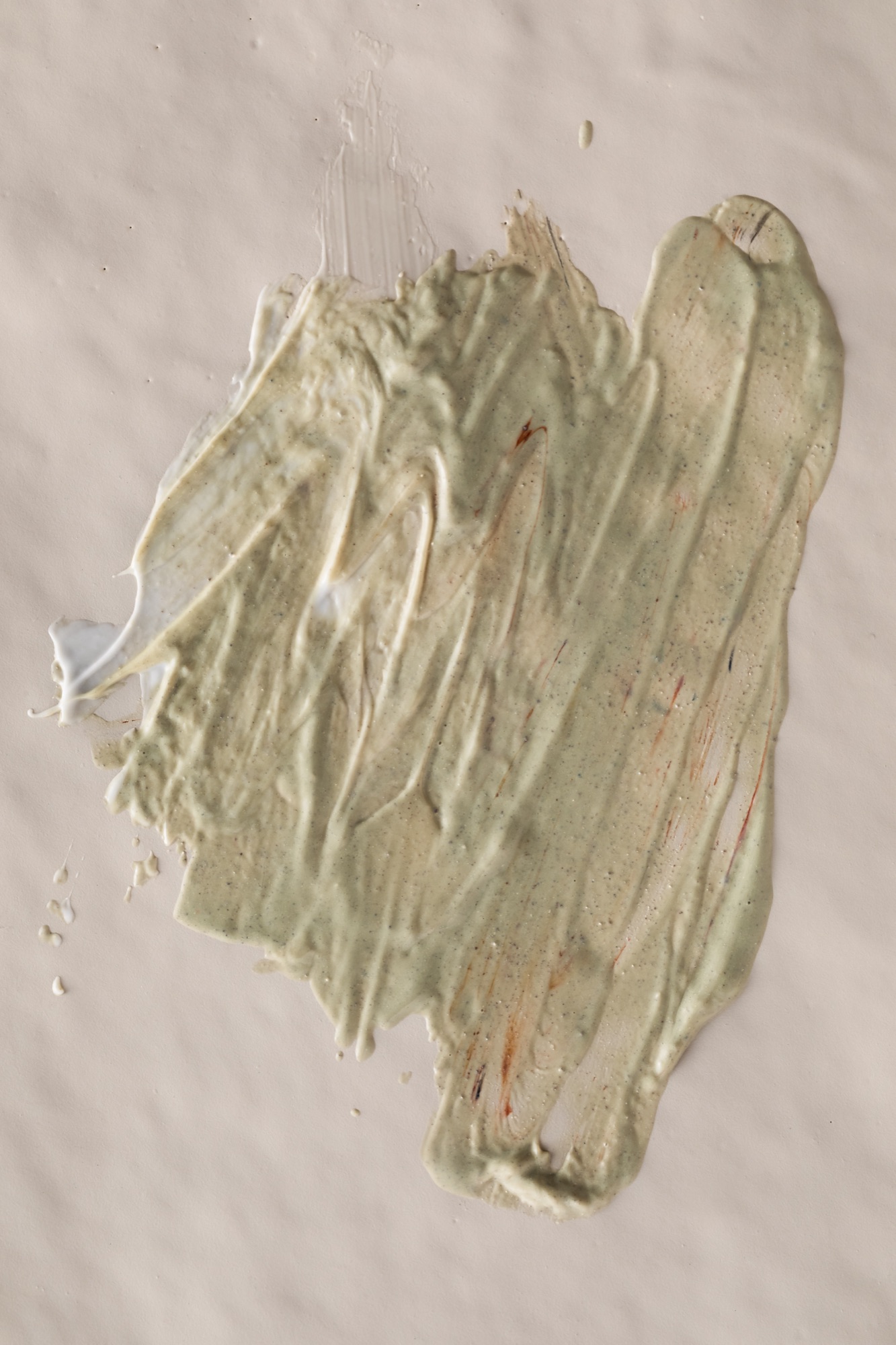 Green clay mask swept across a neutral surface